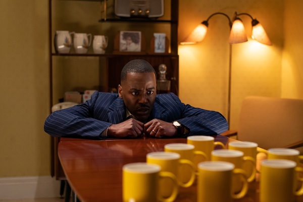 The Doctor looking at the table full of mugs about to slip in Doctor Who's "Wish World"