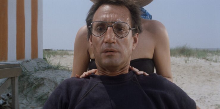 Chief Brody on the beach looking out in fear as a shark attack takes place in a scene from Jaws